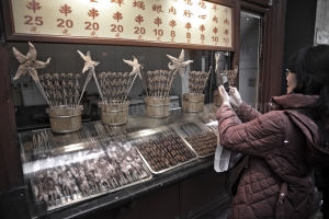 Una mujer china haciendo una foto a un pincho moruno de escorpiones en Pekin